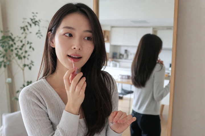 A candid Korean woman applying sheer lip tint at home
