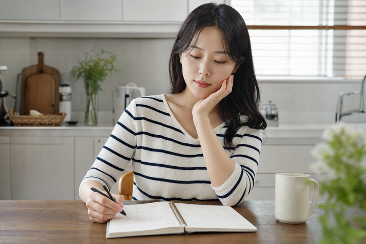 A candid Korean woman planning a simple weekly skincare schedule