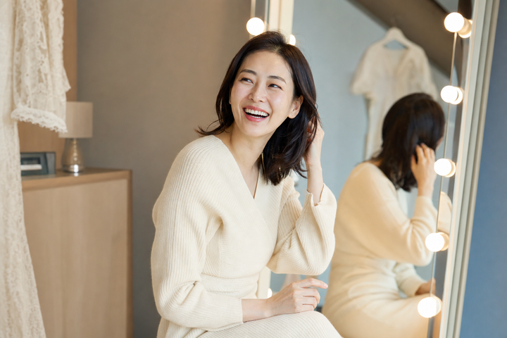 An elegant Korean woman laughing naturally while getting ready